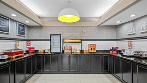 A modern kitchen with dark cabinetry, a central island, and a breakfast bar. - Hampton Inn Bloomington West (Bloomington)