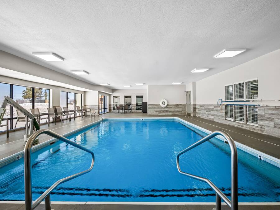 An indoor swimming pool with clear blue water, surrounded by lounge chairs and a stone wall.
