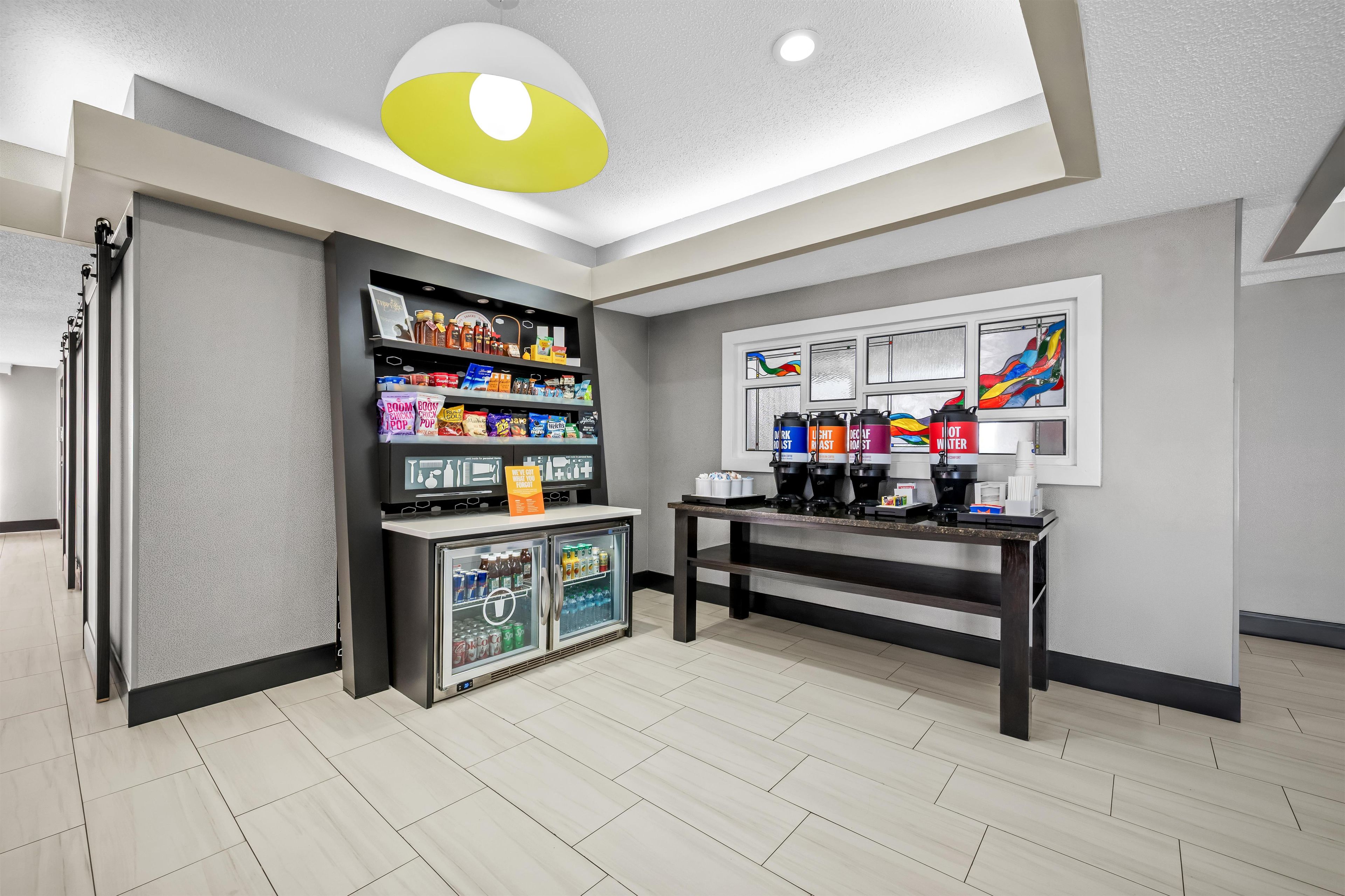 Une chambre moderne équipée d’un coin café, d’étagères pour les collations et d’un réfrigérateur.
