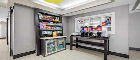 Quarto moderno com espaço para café, prateleiras com lanches e geladeira.