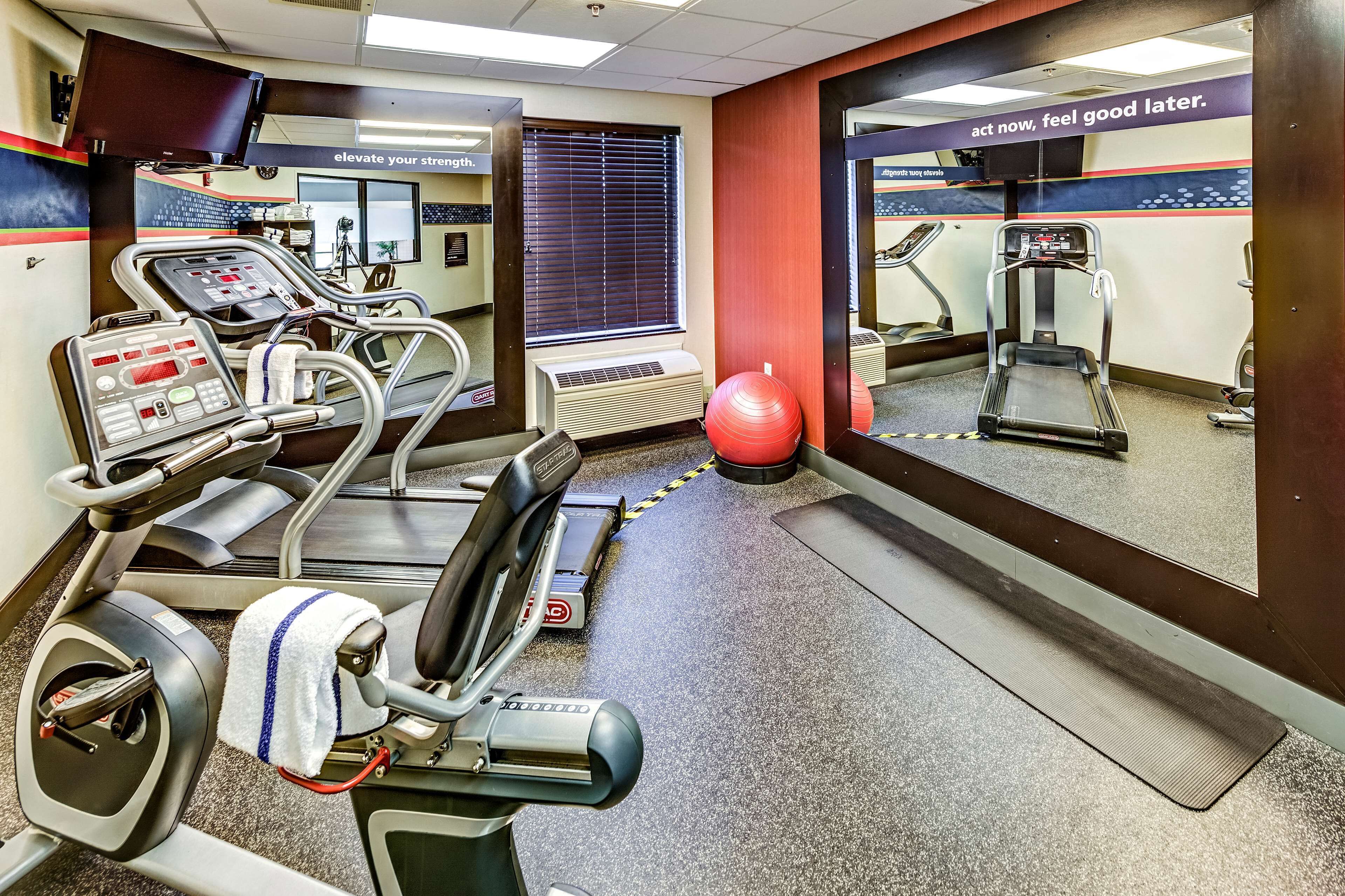 A gym with cardio machines, a red exercise ball, and a treadmill.