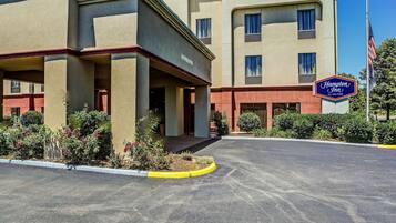 A Hampton Inn by Hilton building with a clear entrance, a parking lot, and a well-maintained landscaping area.