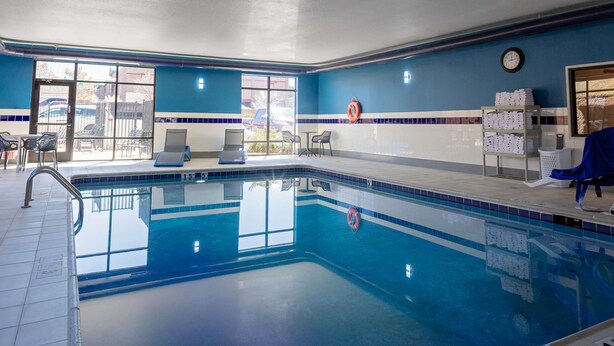 A swimming pool with a tiled deck, chairs, and a lifebuoy on the wall.