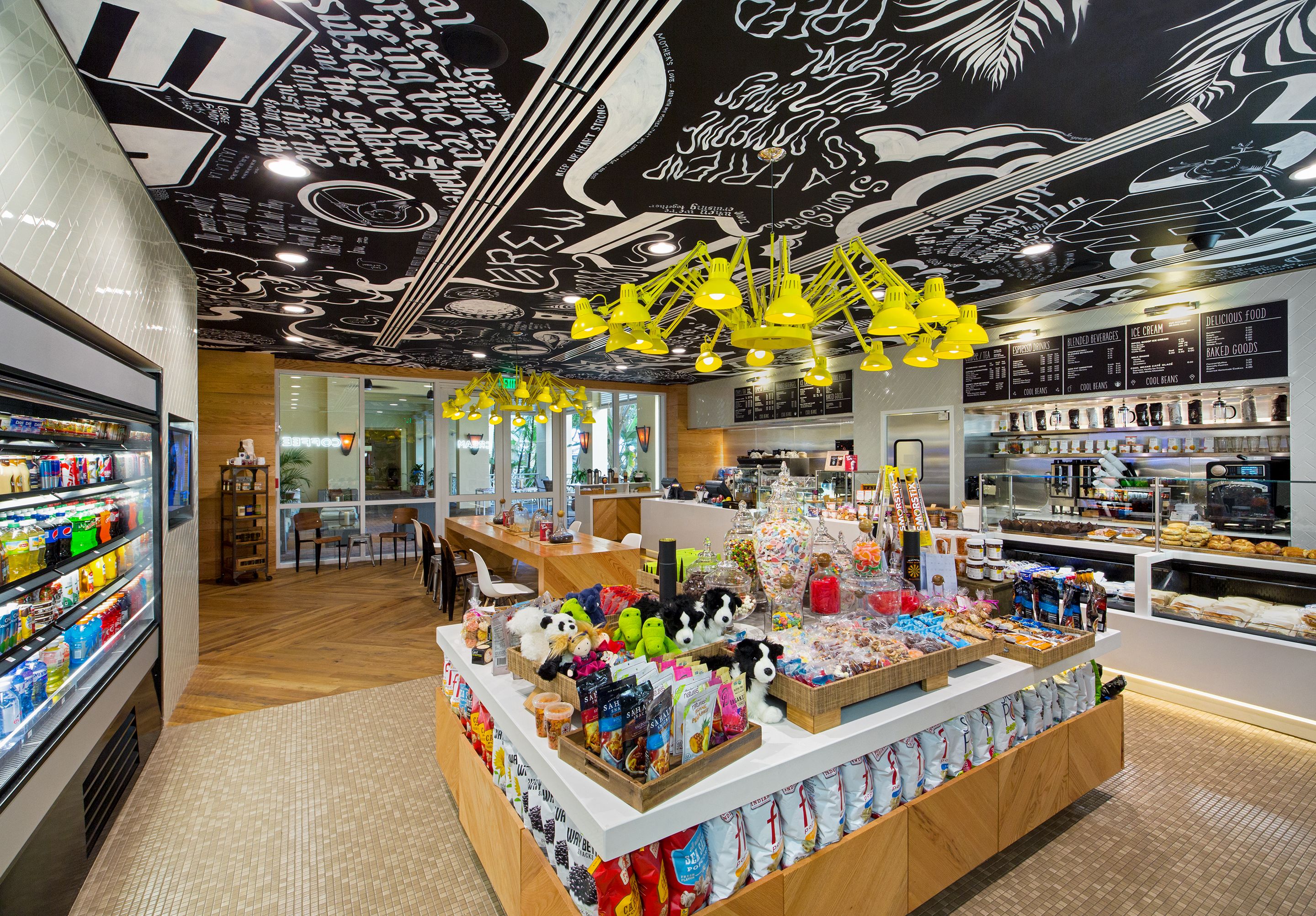Een helder verlichte winkel met een divers aanbod aan producten op planken en toonbanken, waaronder snacks, speelgoed en gebak.