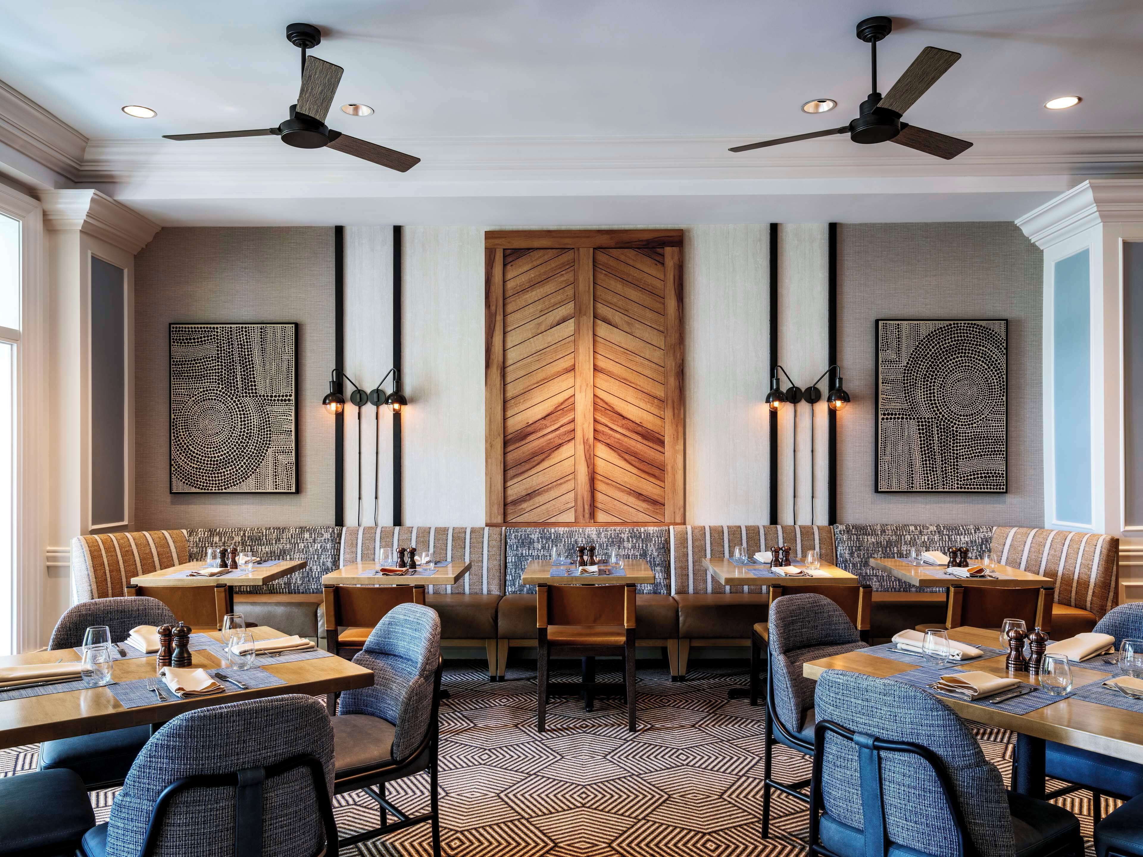 A modern dining area with high ceilings, ceiling fans, and geometric patterned flooring.