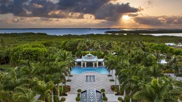 Relax by the serene pool surrounded by lush gardens and palm trees.