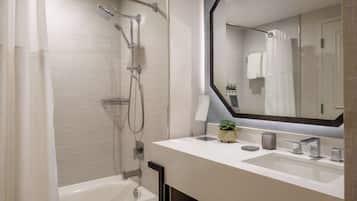 A modern bathroom with a bathtub, a shower with a rain showerhead, and a large mirror above the sink.
