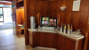 A wooden bar area with a coffee machine, a selection of bottled beverages, and a menu display. - Hotel Stadt Pasing (Munich)