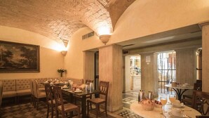 A dining area with a checkered floor, a round table with chairs, and a sofa. - Hotel Donatello (Rome)