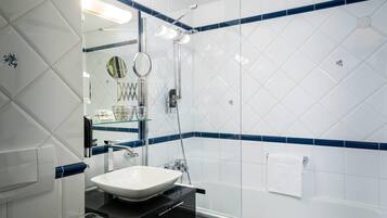 Un baño con lavamanos blanco, espejo y cabina de ducha de vidrio.