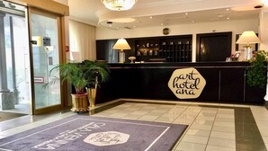 A hotel reception area with a reception desk, two lamps, a sign reading 'part hotel ana', and a doormat with a logo. - Arthotel ANA Gala, Trademark Collection by Wyndham (Vienna)