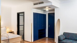 A hotel room with a bed, a desk, a blue wardrobe, and a patterned sofa. - Arthotel ANA Gala, Trademark Collection by Wyndham (Vienna)