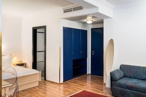 A hotel room with a bed, a desk, a blue wardrobe, and a patterned sofa. - Arthotel ANA Gala, Trademark Collection by Wyndham (Vienna)