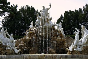 Une grande fontaine extérieure ornée de nombreuses statues et de jeux d’eau.