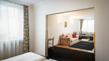 A hotel room with a bed, a desk, a sofa, and a dining area.