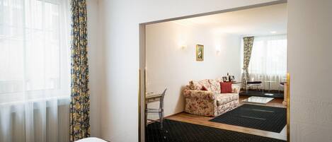 A hotel room with a bed, a desk, a sofa, and a dining area.