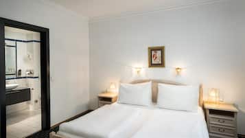 Een hotelkamer met een bed, twee nachtkastjes, een spiegel en een lijst met een foto aan de muur.