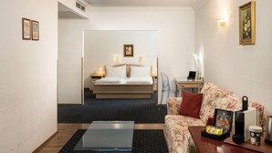 A hotel room with a bed, a sofa, a coffee table, and a desk with a computer. - Arthotel ANA Gala, Trademark Collection by Wyndham (Vienna)