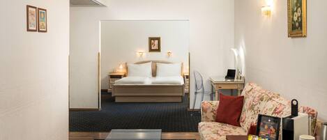 A hotel room with a bed, a sofa, a coffee table, and a desk with a computer.