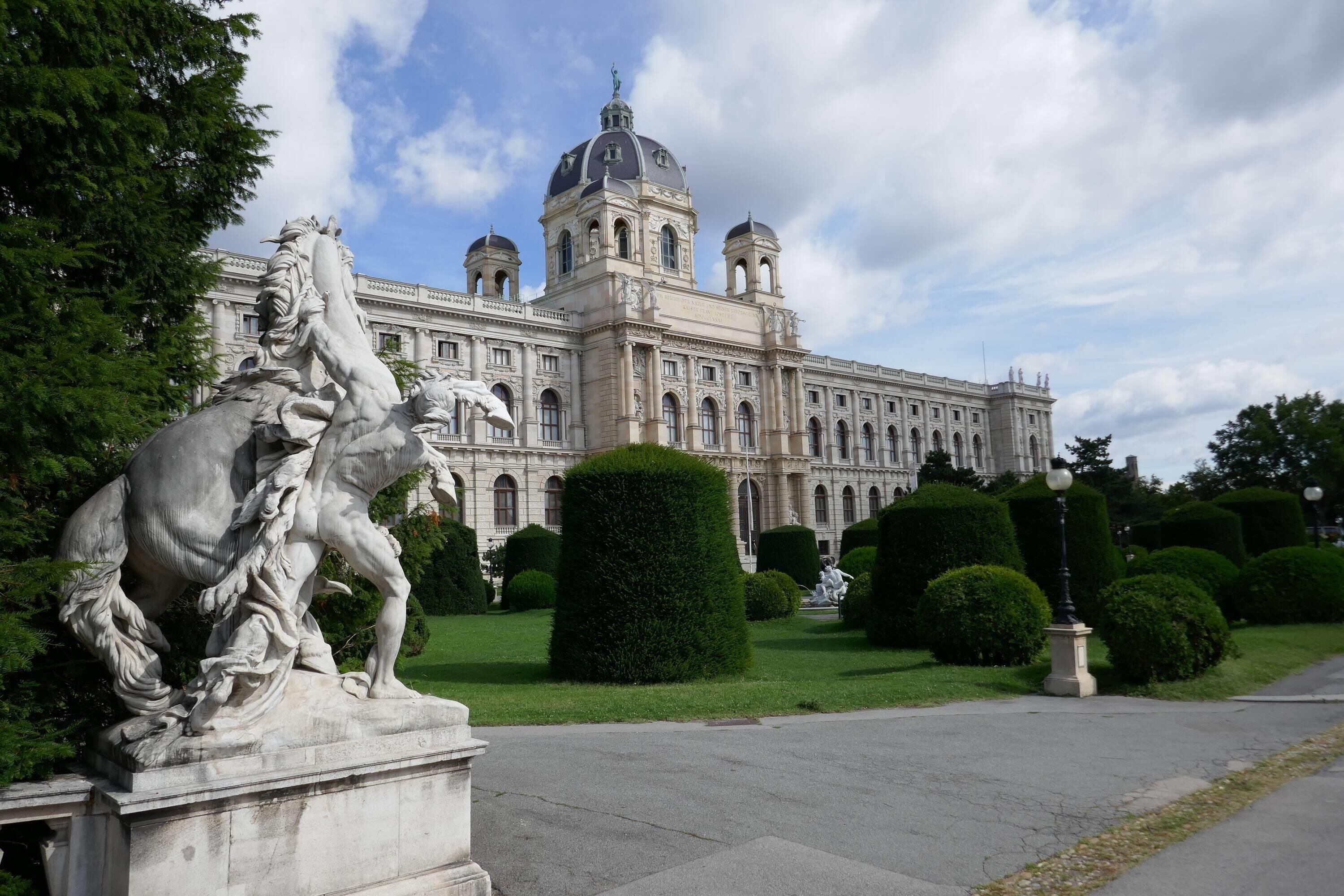 Ein klassizistisches Gebäude mit einer großen Kuppel und Statuen im Vordergrund.
