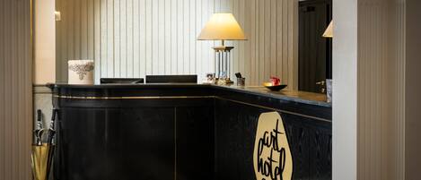 A hotel reception desk with a black counter, a lamp, and a sign that reads 'part of the hotel chain.'