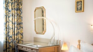 A hotel room with a vanity, a mirror, a lamp, and a bed. - Arthotel ANA Gala, Trademark Collection by Wyndham (Vienna)