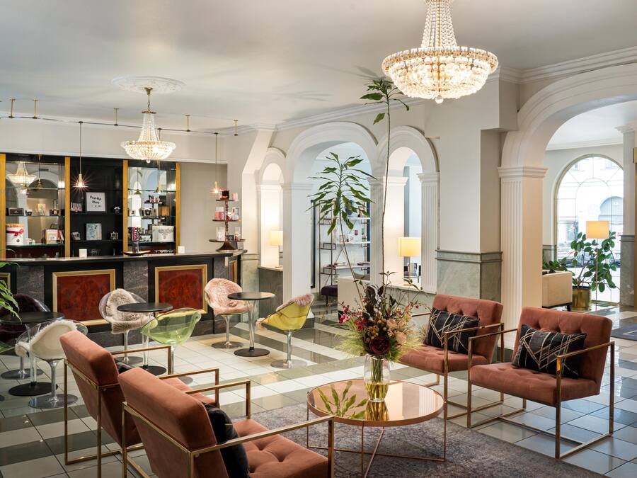 A spacious lobby with a bar area, seating arrangements, and a chandelier.