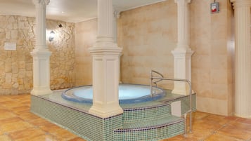 A spa area with a hot tub, stone walls, and columns.