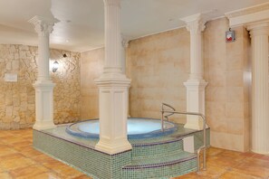 A spa area with a hot tub, stone walls, and columns.