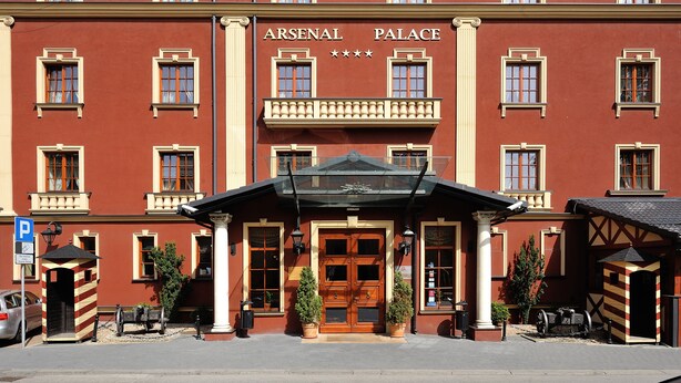 Ein rotes Gebäude mit der Aufschrift "ARSENAL PALACE" und mehreren Fenstern.