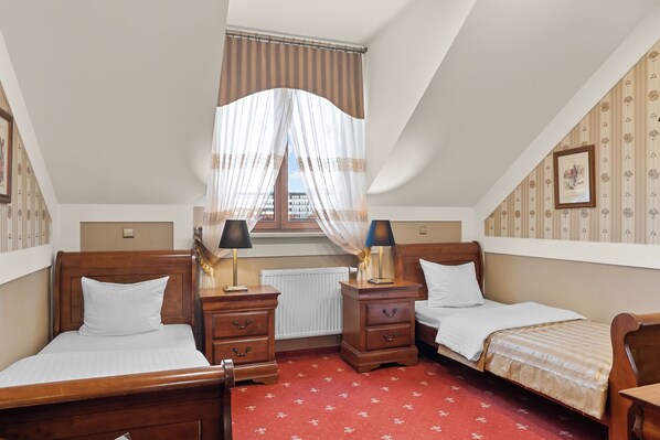 Un dormitorio con dos camas de madera, una alfombra roja, una ventana con cortinas traslúcidas y un radiador.