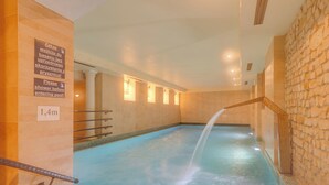 Ein Hallenbad mit einer Tiefenanzeige von 1,4 Metern, einer Dusche vor dem Becken und einer Steinwand.