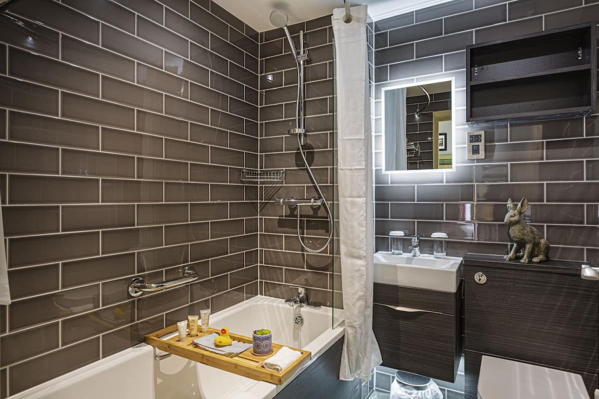 A modern bathroom with a bathtub, shower, and vanity.