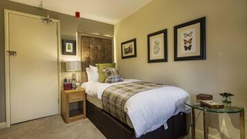 A bedroom with a bed, bedside table, lamp, and framed pictures on the wall.