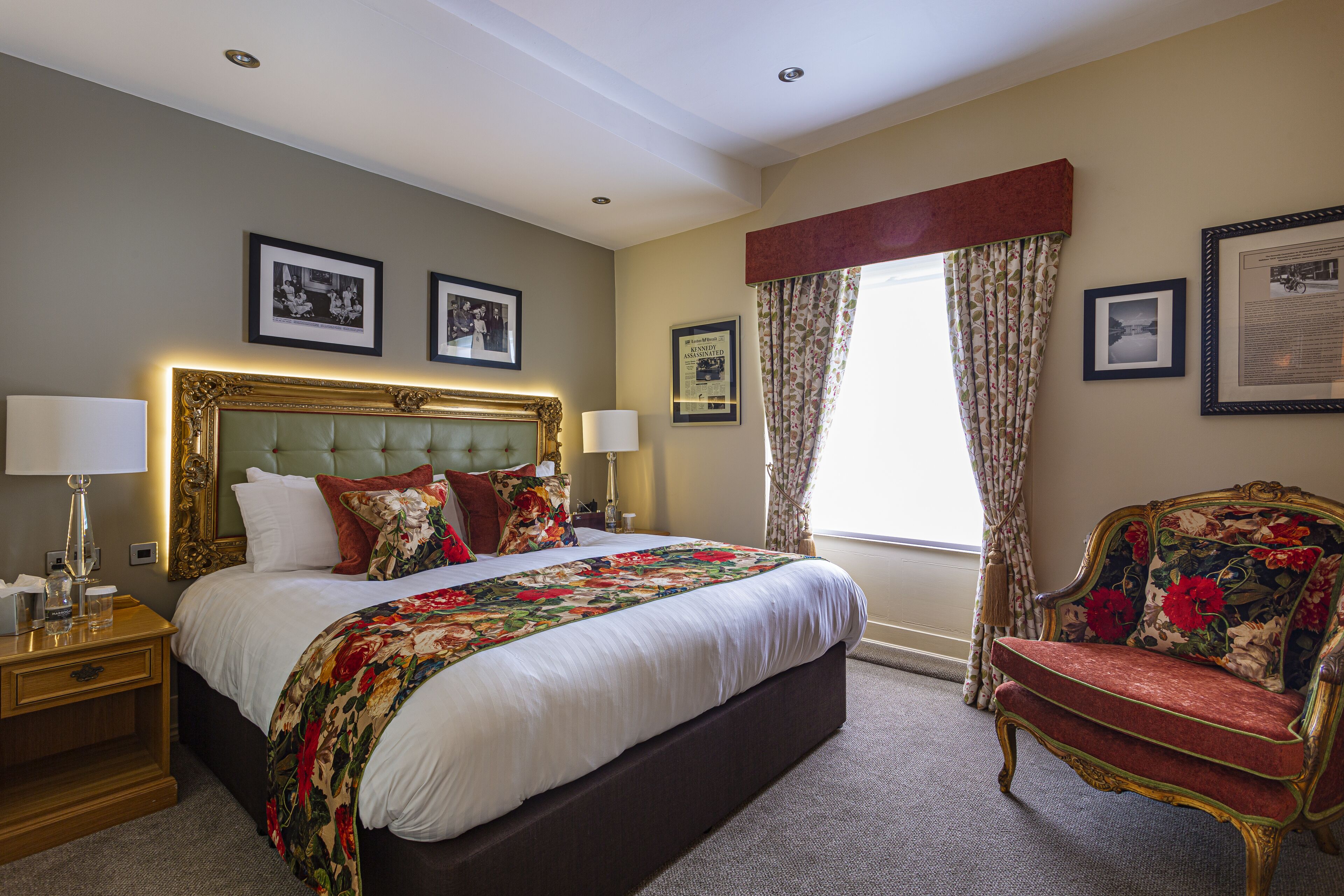 A hotel room with a large bed, a nightstand, a chair, and a window with curtains.