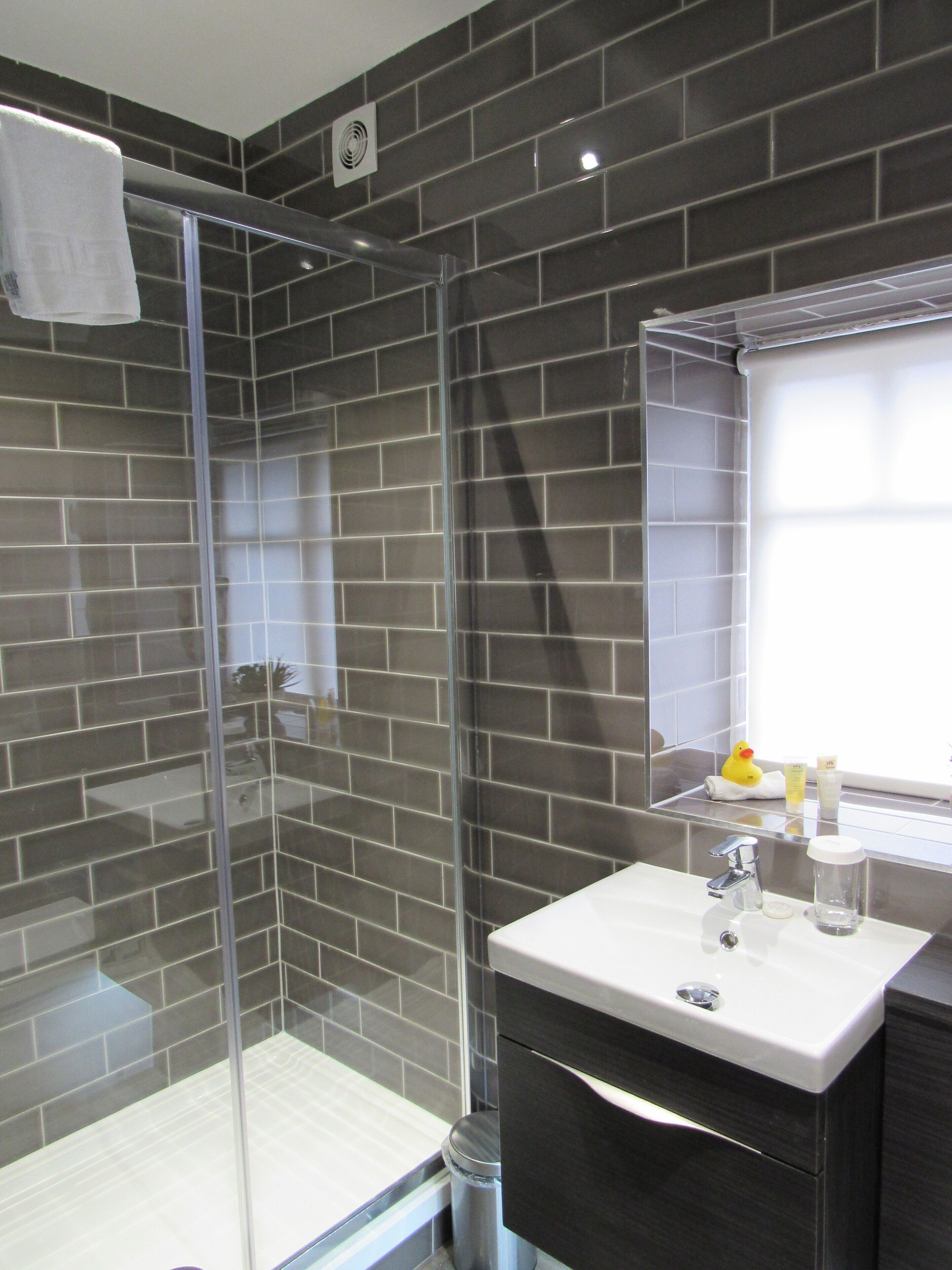 A modern bathroom with a glass-enclosed shower, a white sink, and a dark-toned vanity.