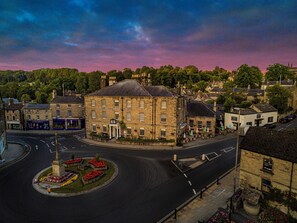 A historic building with a central courtyard, a roundabout, and a street with shops.