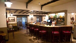 A bar area with a counter, stools, and a bar stocked with bottles.