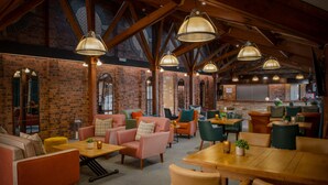 A spacious interior with high ceilings, exposed brick walls, and a mix of seating areas including sofas and tables.