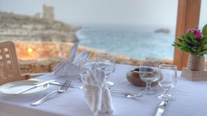 Mesa para dos con vista al mar y un castillo al fondo.