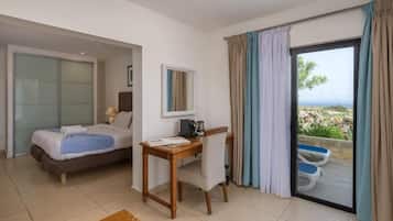 Habitación de hotel con cama, escritorio, silla, ventana con cortinas y vistas al exterior.