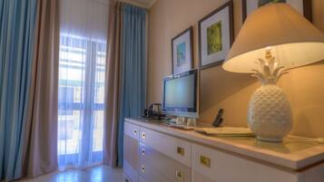 A hotel room with a TV, a lamp, a decorative vase, and a window with curtains.