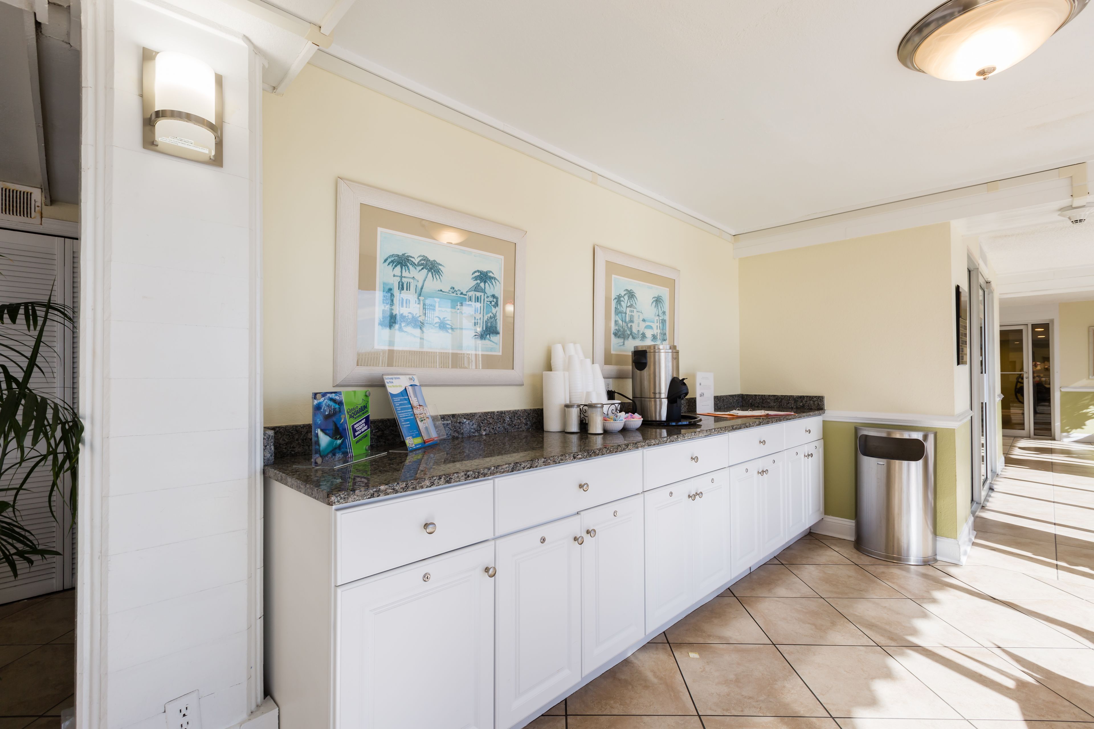 A kitchen with white cabinets, granite countertops, and two framed pictures on the wall.