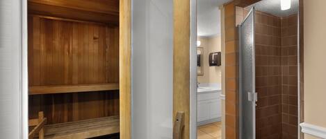 A wooden sauna with benches, a glass shower enclosure, and a white sink.