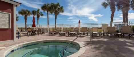 A pool area with lounge chairs, palm trees, and a lifeguard sign.
