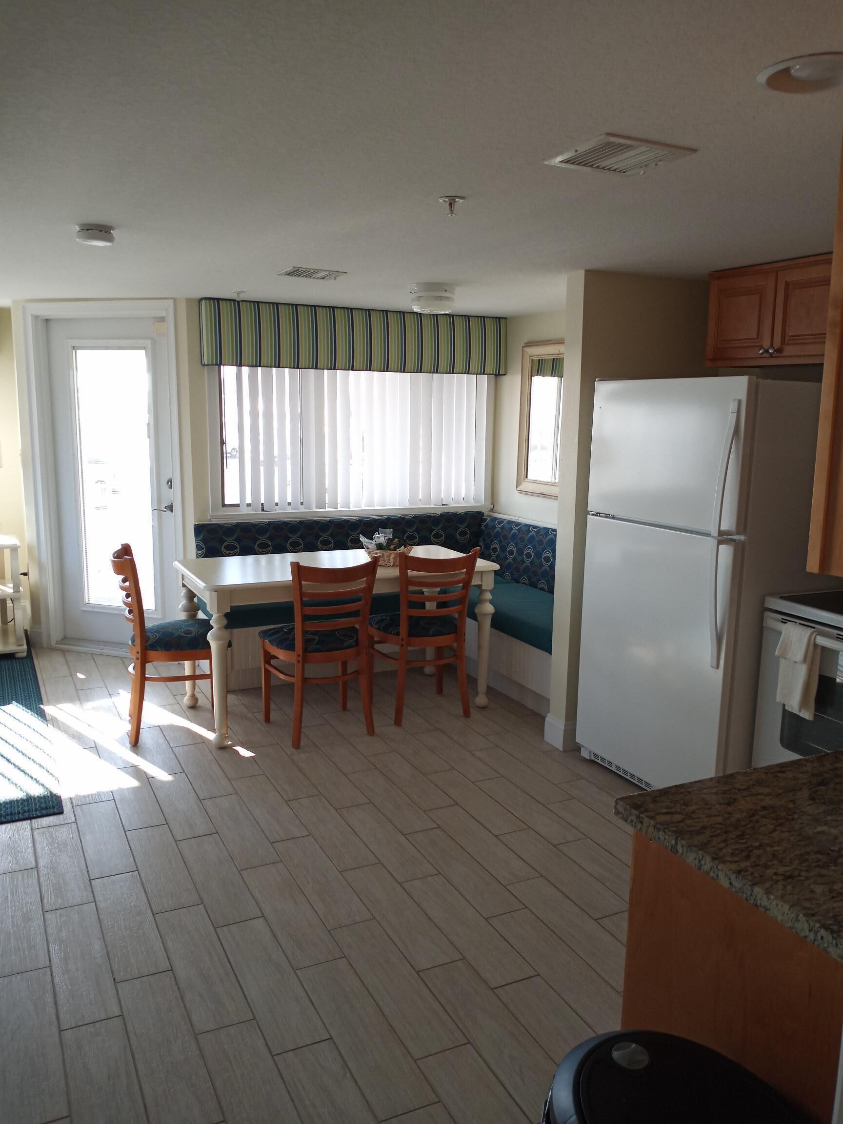 Una cocina compacta con una mesa y sillas, un refrigerador y una ventana con persianas.