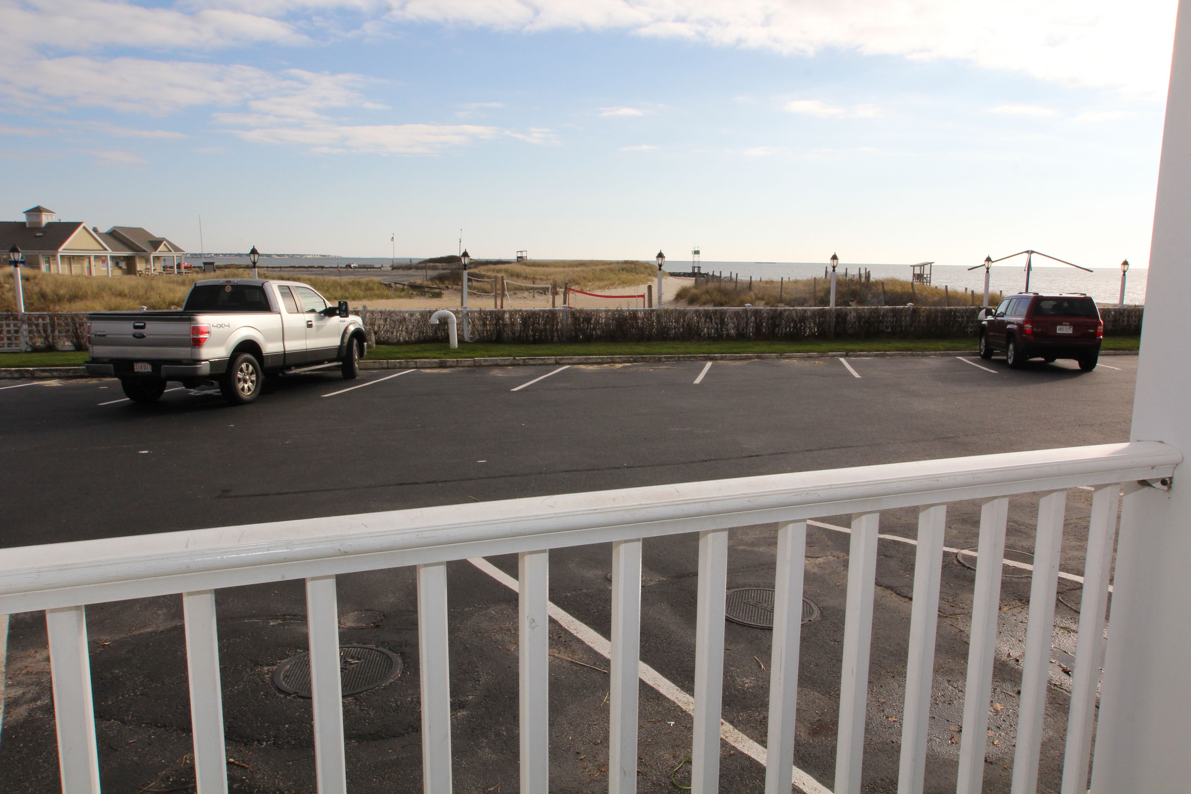 A parking lot with a white pick-up truck and a maroon SUV.