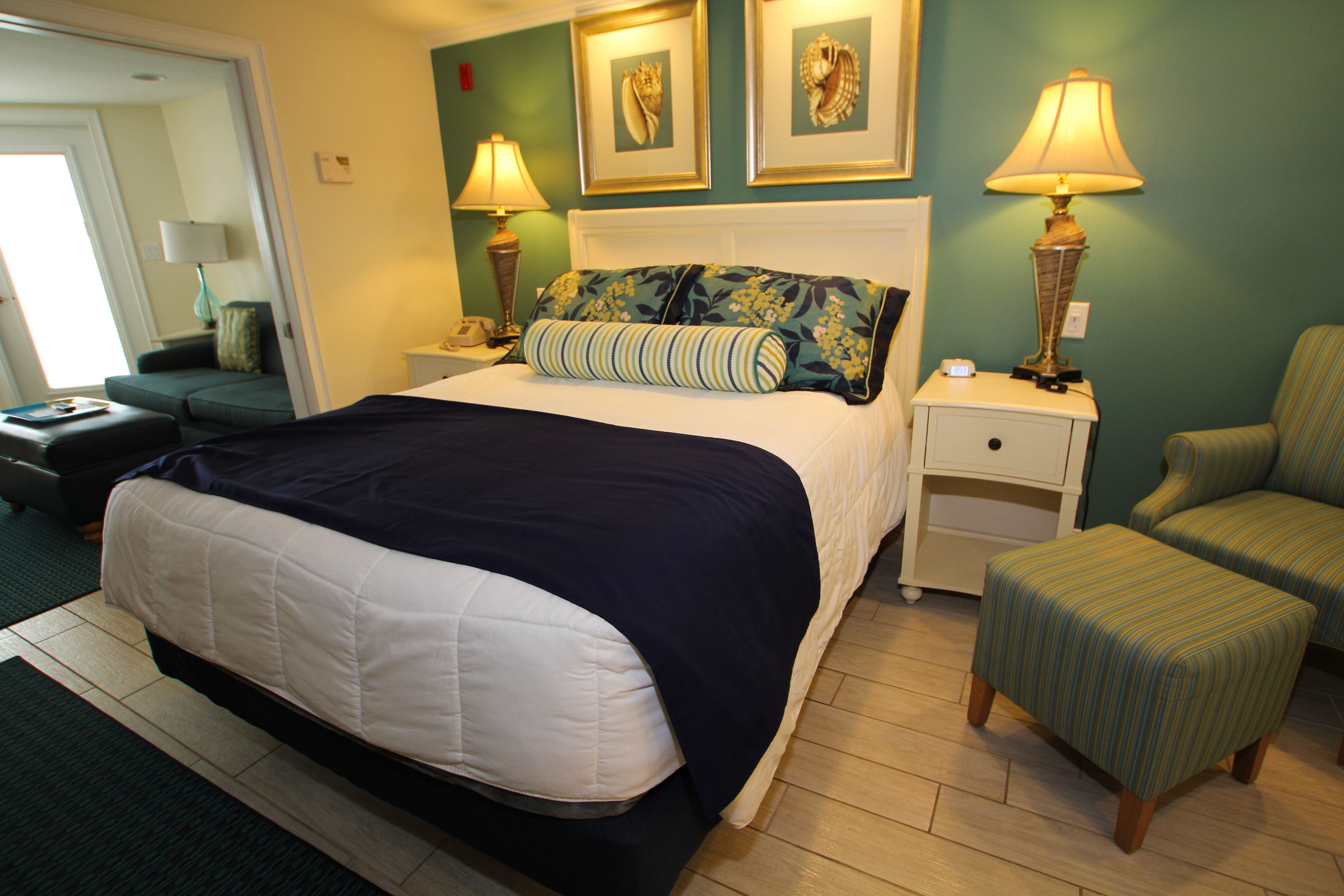 A neatly arranged hotel room with a bed, two bedside tables with lamps, a chair, and a small table.