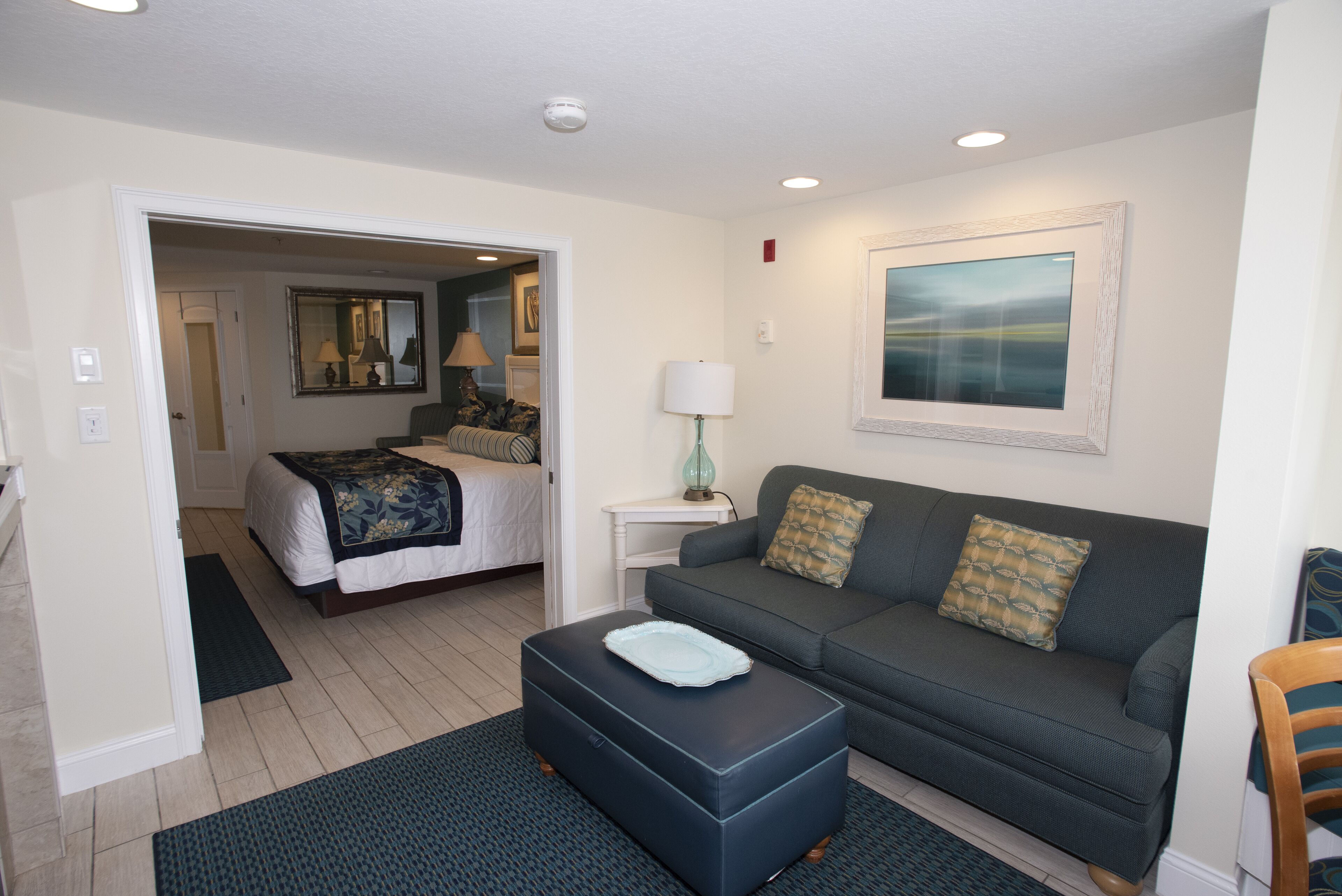 A bedroom with a bed, a nightstand, a lamp, and a window.