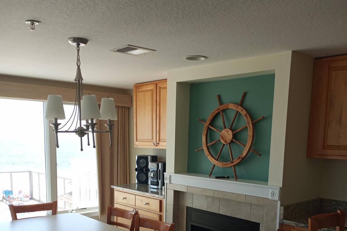 Une cuisine spacieuse avec un coin repas, des meubles en bois, une décoration en forme de roue de navire et une cheminée.